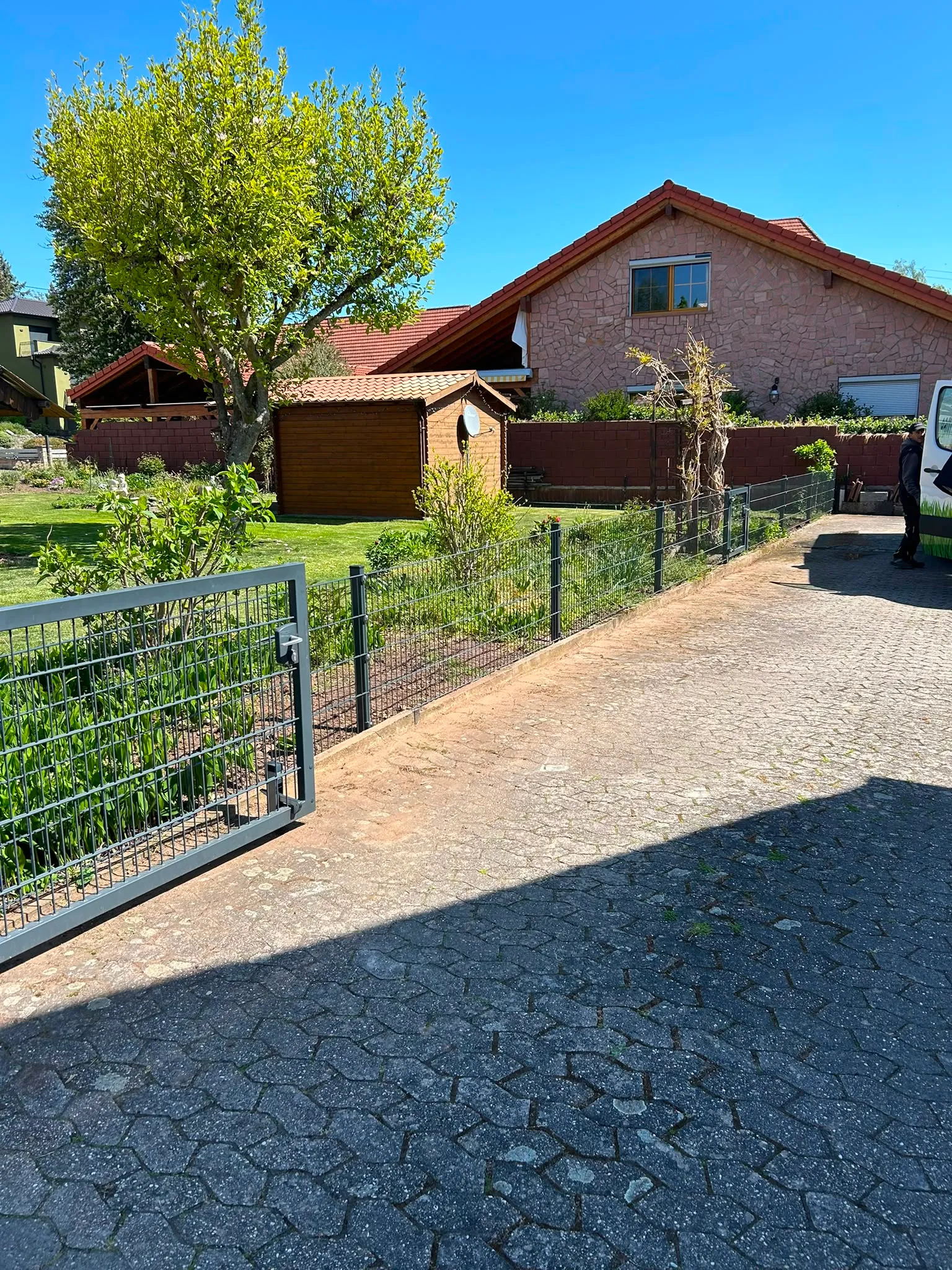 Anthrazitfarbenes Doppelstabmatten-Tor an einer Grundstückseinfahrt.