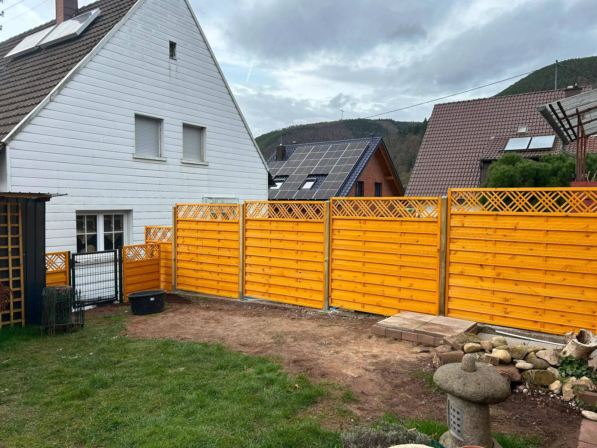 Sichtschutzzaun aus Holz mit Rankgitter-Aufsatz im Garten.